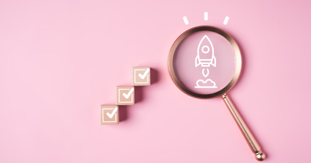 Magnifying glass over rocket icon, checklist cubes nearby.