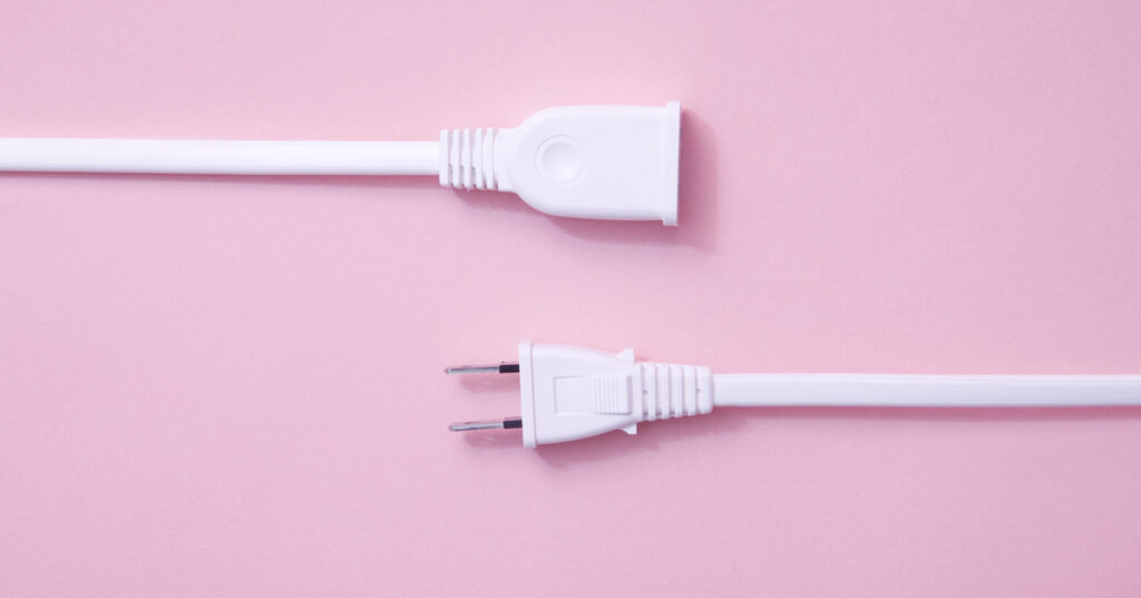 Disconnected white power plug and socket on pink background.