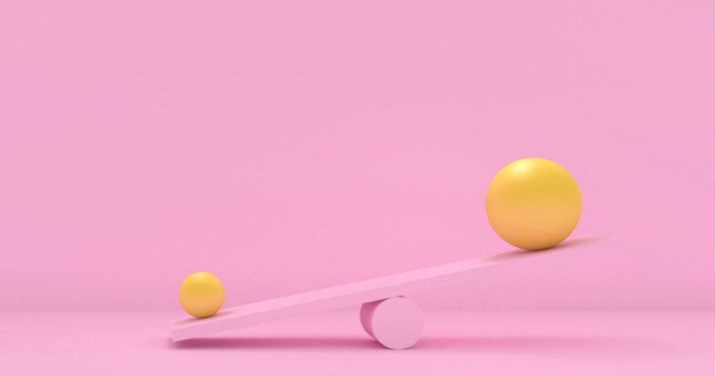 Yellow balls balancing on pink seesaw