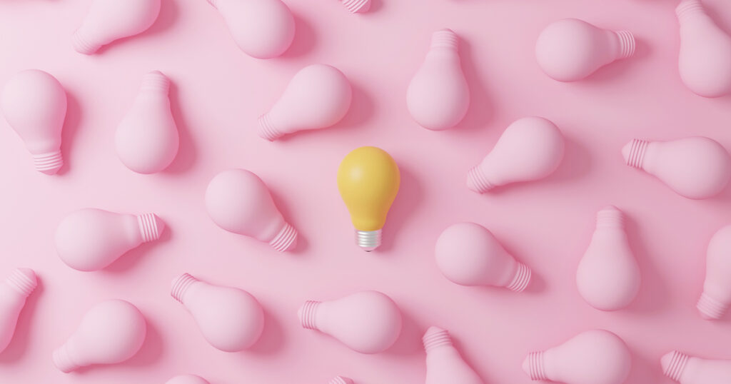 Yellow bulb among pink bulbs on pink background