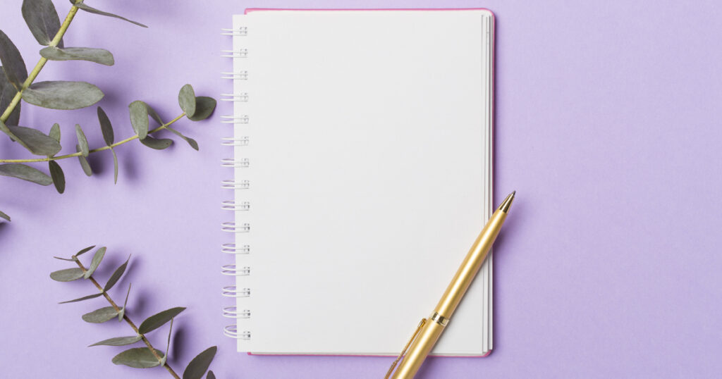 Notebook with pen on purple background