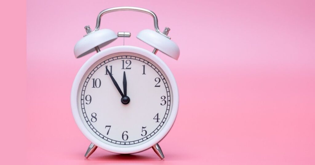 White alarm clock on pink background