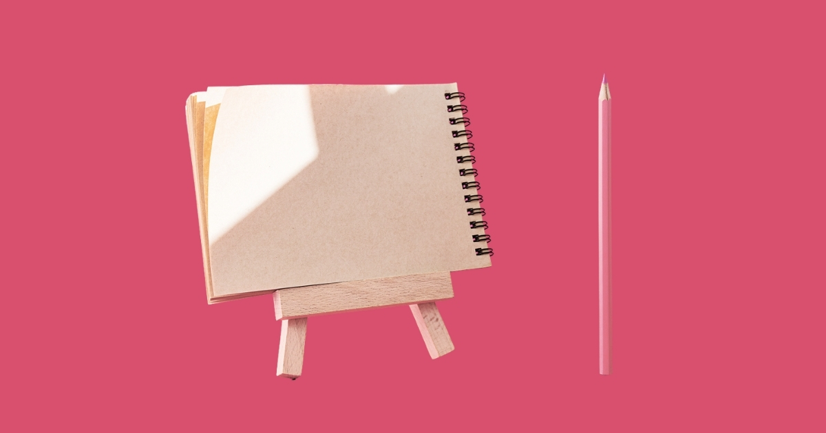 Pink pencil beside spiral notebook on easel