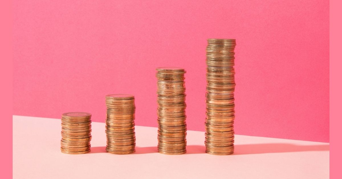 Increasing stacks of coins on pink background.