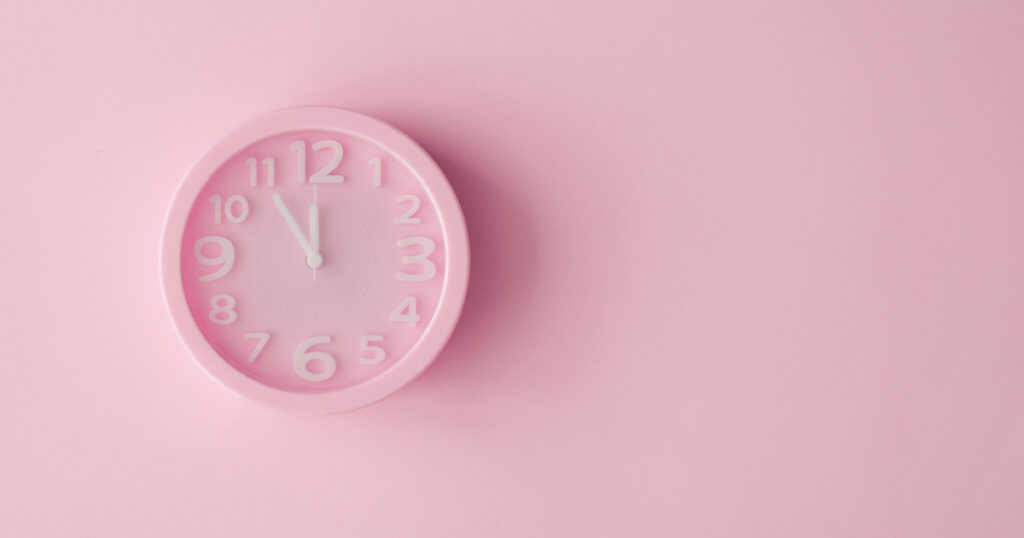 Pink clock on pink background showing 10:10