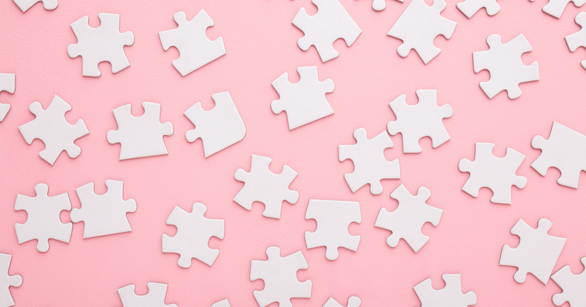 Scattered white puzzle pieces on pink background.
