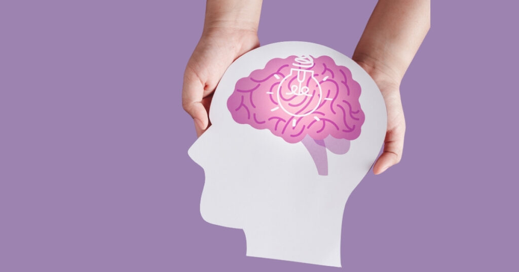Hands holding brain cutout with light bulb