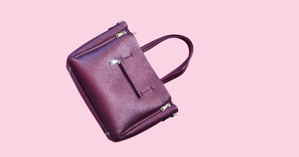 Stylish purple handbag on pink background.