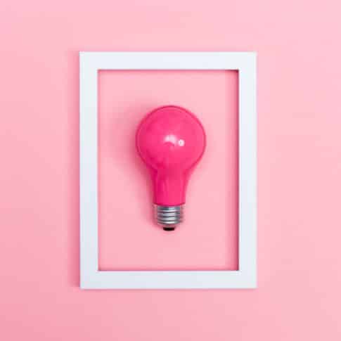Colored lightbulb on a pink background with frame