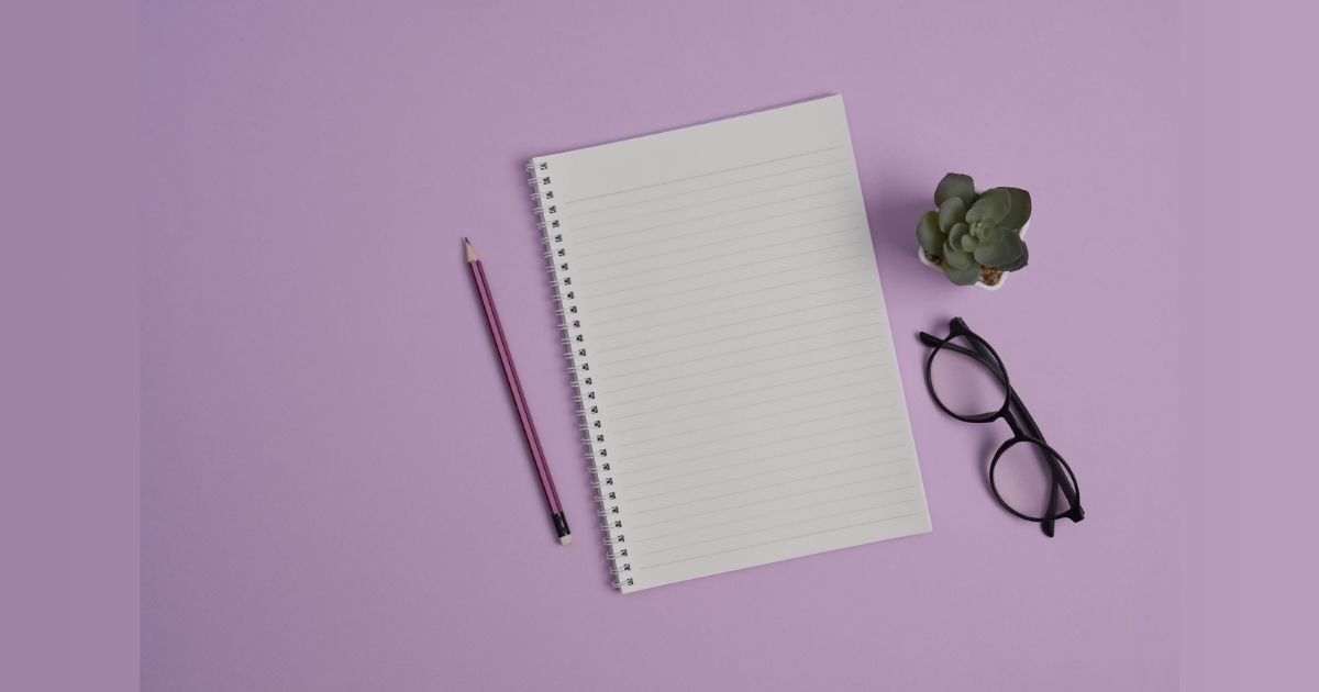 Notebook with pencil, glasses, and succulent on purple background.