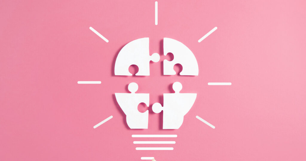 Lightbulb made of puzzle pieces on pink background