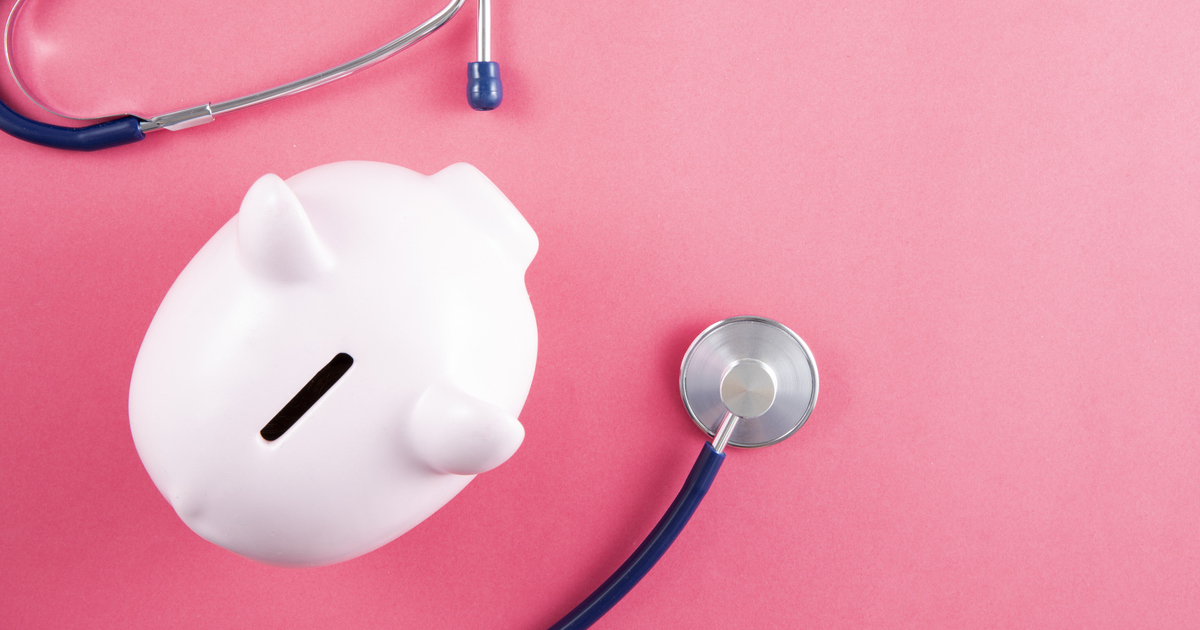 Stethoscope and piggy bank on pink background with copy space
