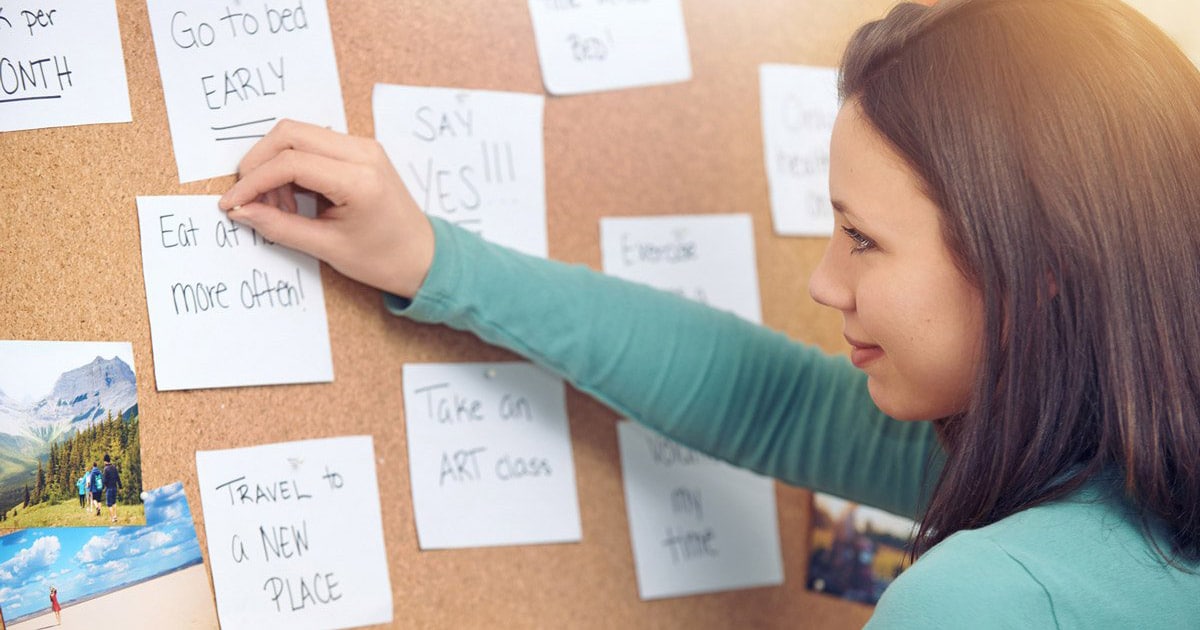 young woman pinning notes on a bulletin board