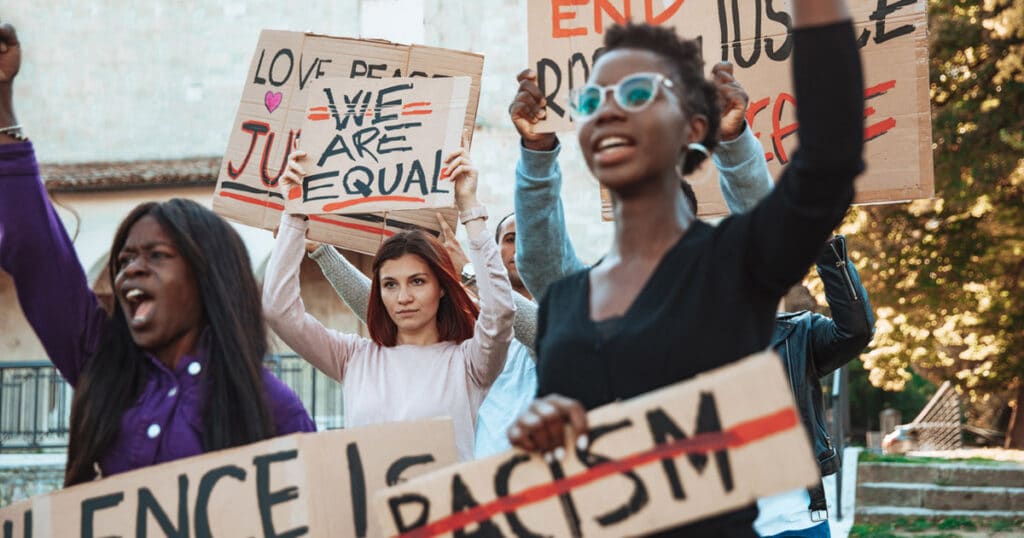 diverse group of anti-racism protesters holding handmade cardboard signs