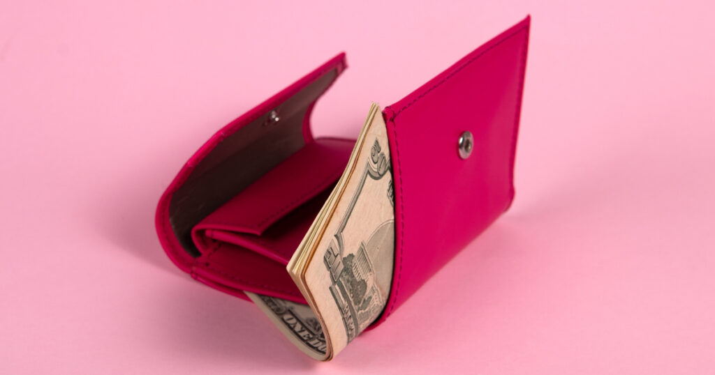 Pink wallet with cash on pink background