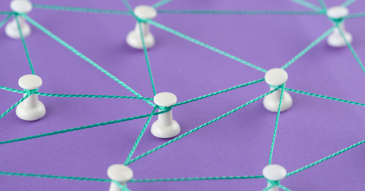 Network concept with pins and string on purple backdrop.