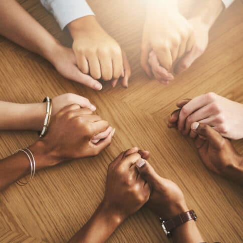 diverse group of hands joined together at table