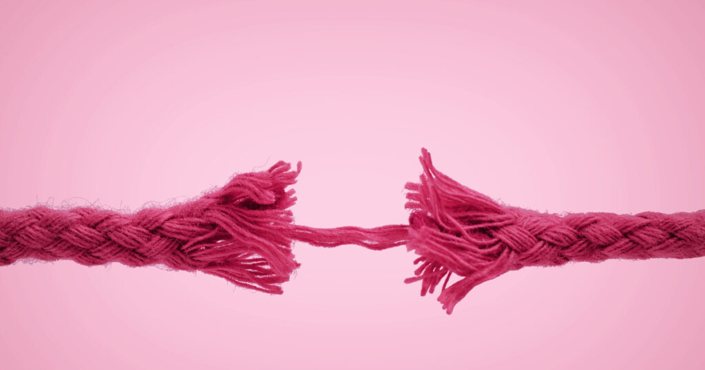 Frayed pink rope breaking apart on pink background.