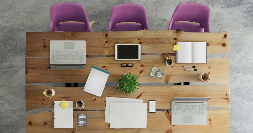 Wooden office desk with laptops, tablet, and stationery.