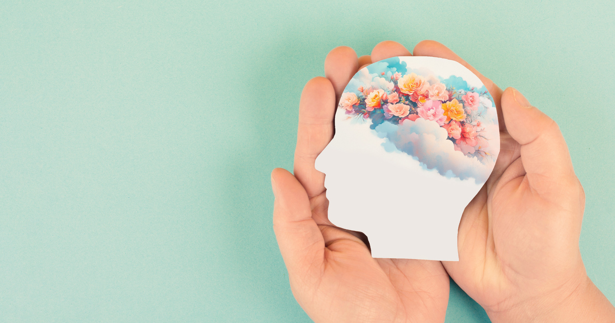 Hands holding head silhouette with flowers inside.