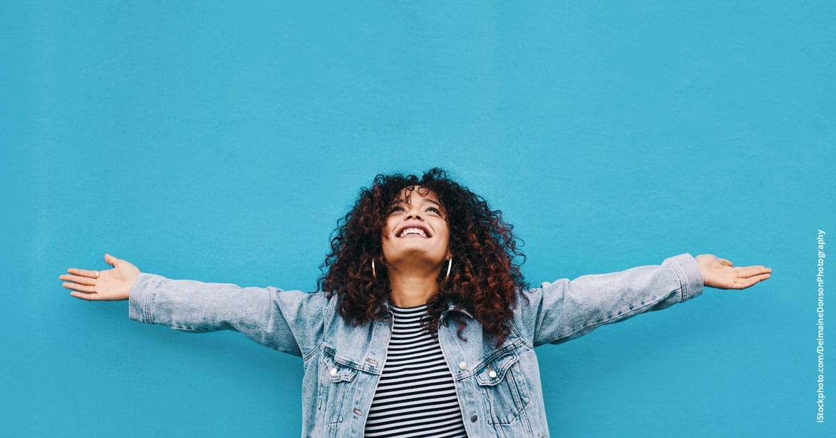 cheerful woman standing with her arms outstretched against a blue background