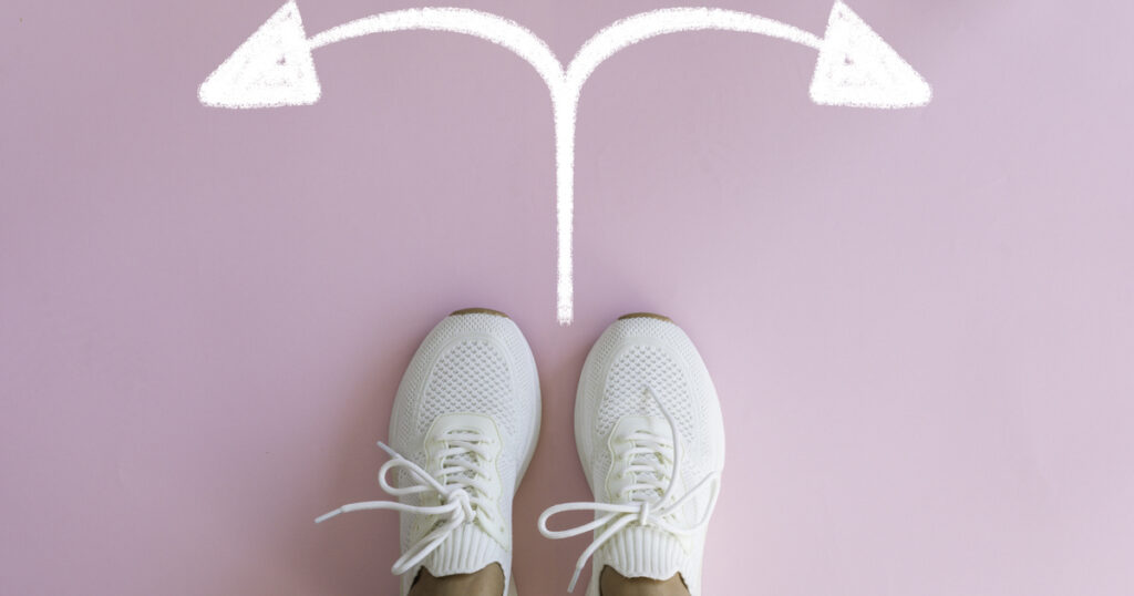 White sneakers facing two arrows on pink background.