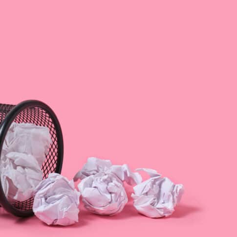 Rashes of crumpled paper from trash can, on pink background