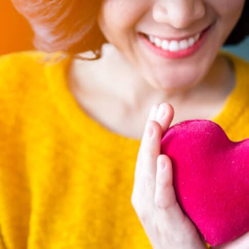 close up of a woman's hands holding a pink plush heart