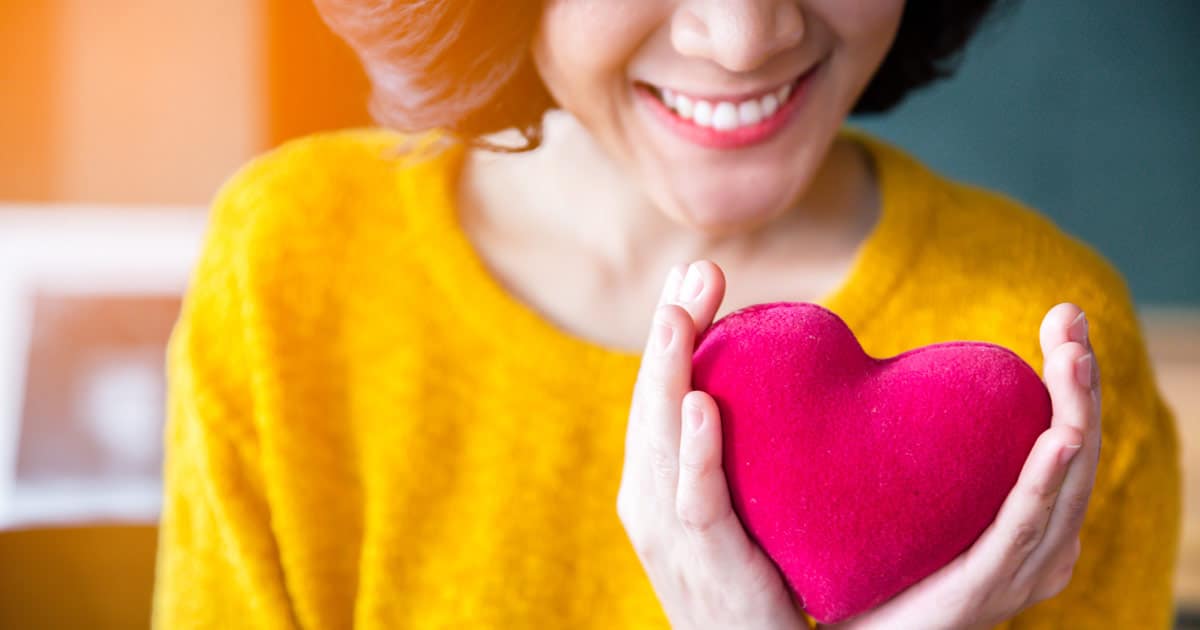 close up of a woman's hands holding a pink plush heart