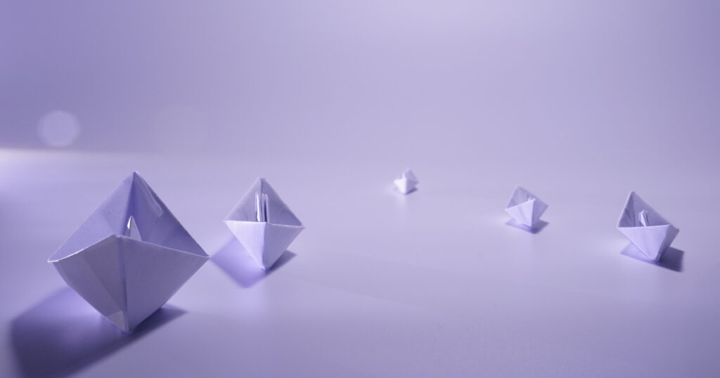 Purple origami boats on smooth surface.
