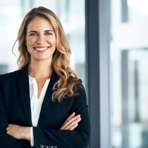 confident female executive standing with arms crossed in modern office