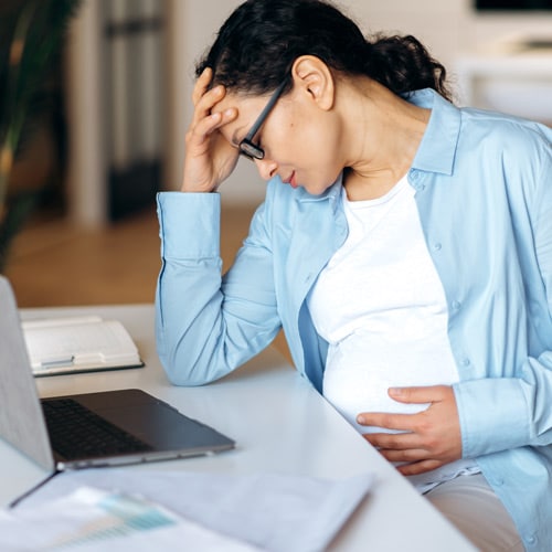 exhausted pregnant woman sitting at home office desk, thumbnail