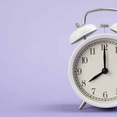 Retro alarm clock on purple or violet table background, vintage style, flat lay