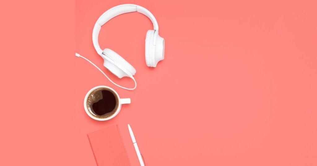 Headphones, coffee, notebook, pen on orange background
