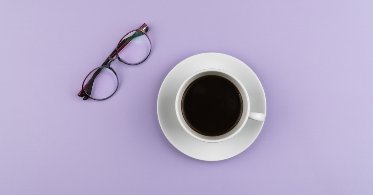 Coffee cup and glasses on purple background.