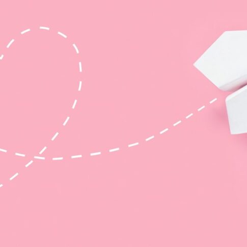 Paper airplane on pink background with heart shaped flight path