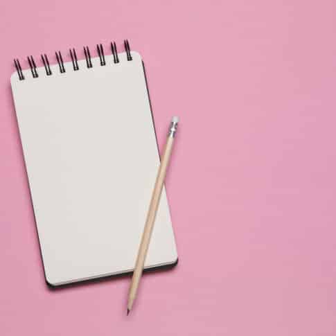 Spiral notebook and pencil isolated on pink background