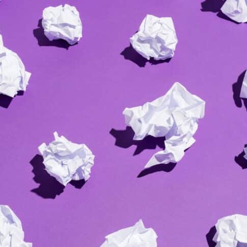 White balls of creased paper laying on a bright violet background. Recycling concept.