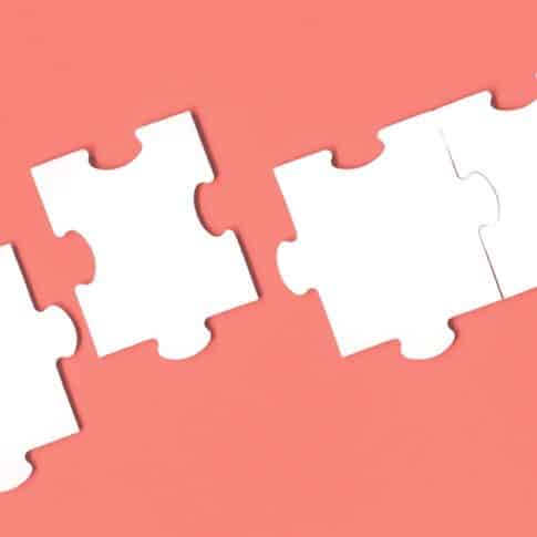 Jigsaw puzzle matching pieces. Teamwork and solution or idea concept with copy space on trendy pastel living coral background