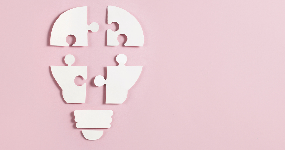 Puzzle pieces forming a light bulb on pink background.