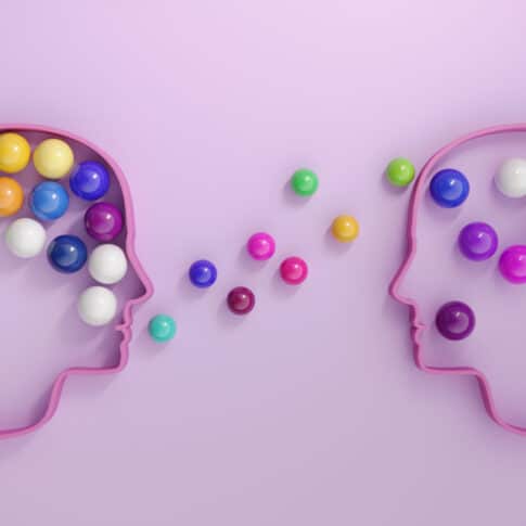 Human heads includes lots of multi colored spheres, symbolizing communication concepts.