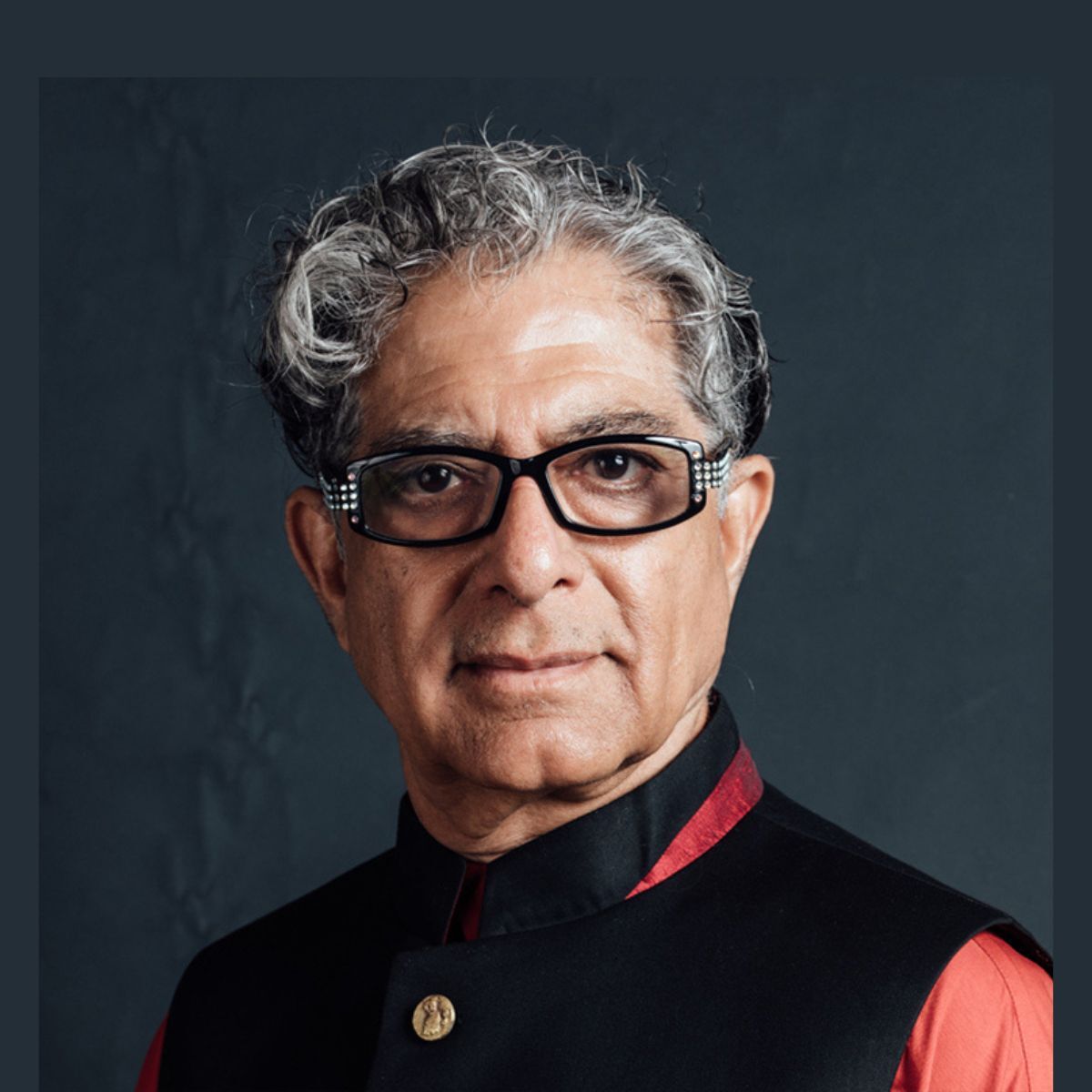 Person wearing glasses and black traditional outfit.