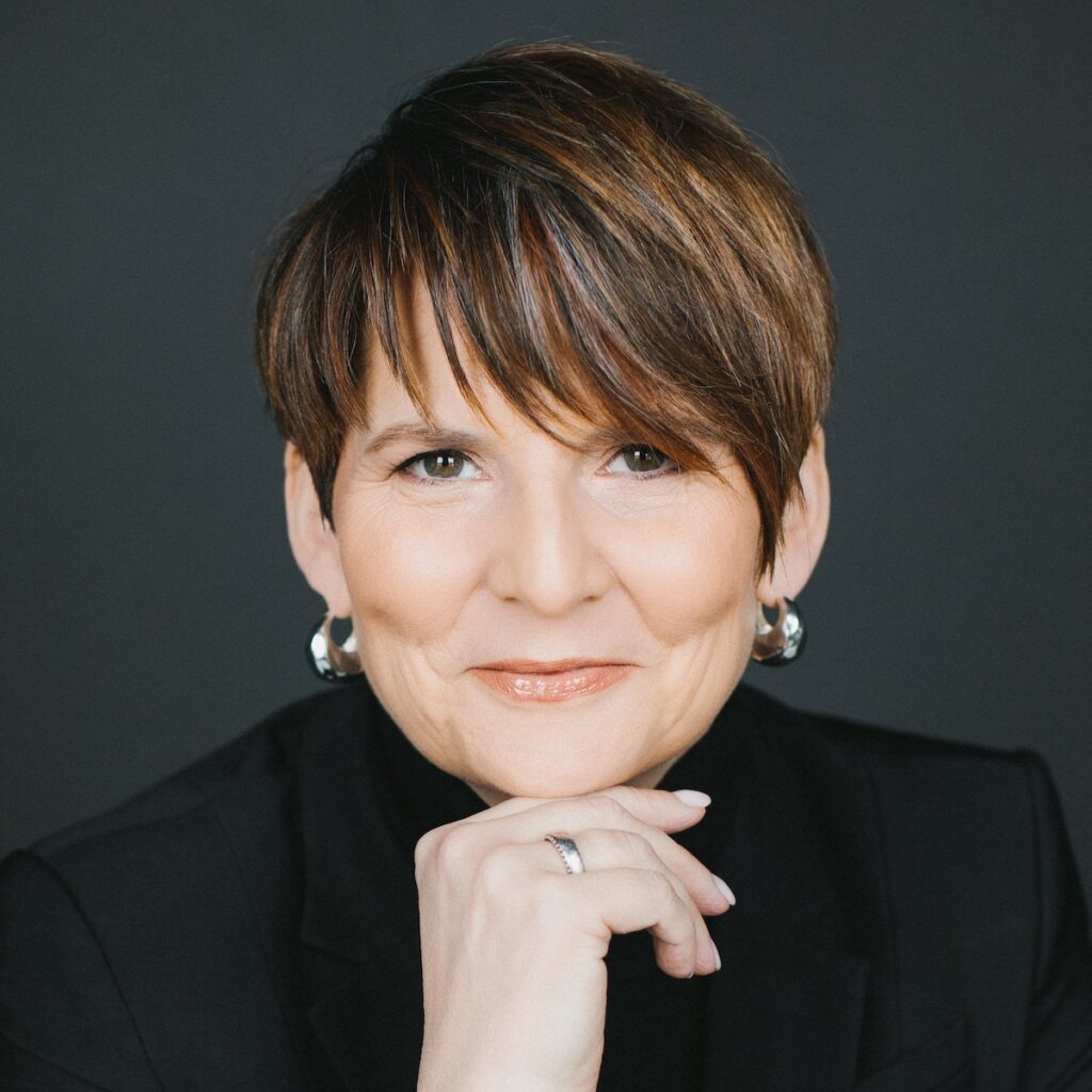 Professional portrait of smiling woman in black suit.