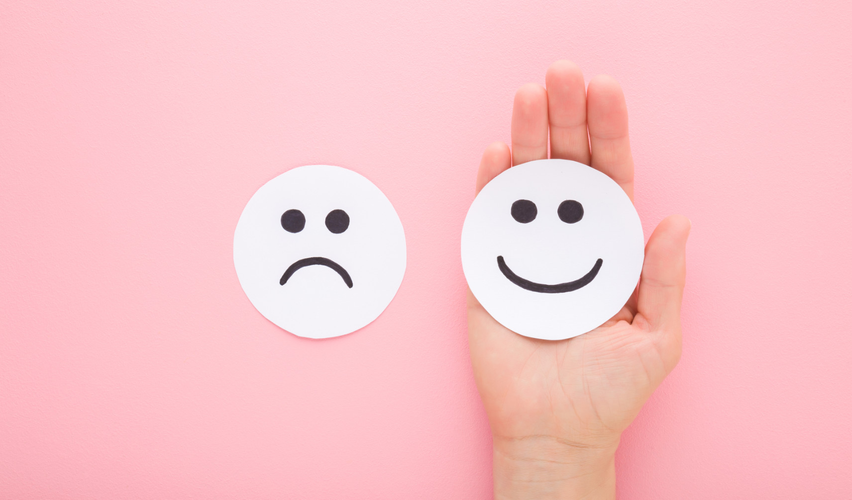 happy and sad face paper cutouts on pink background