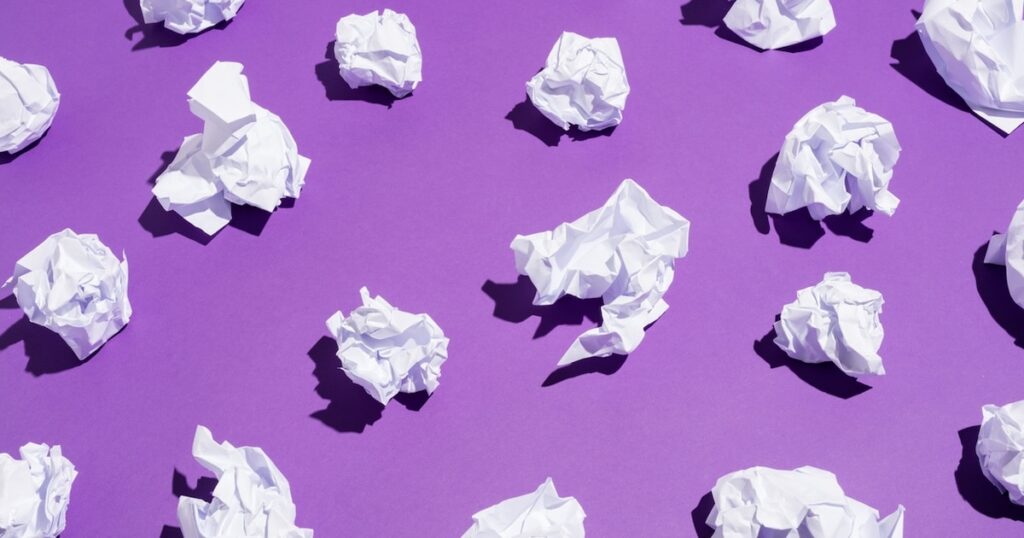 White balls of creased paper laying on a bright violet background. Recycling concept.