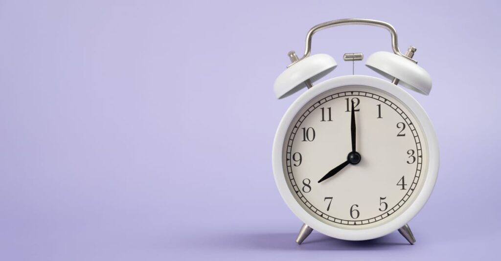 Retro alarm clock on purple or violet table background, vintage style, flat lay