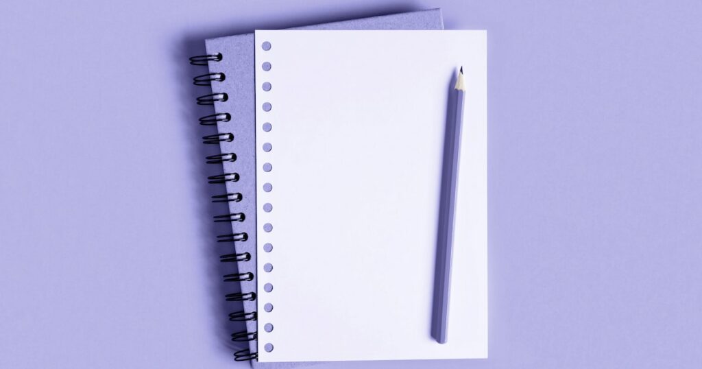 Lavender notebook and pencil on top of lavender background