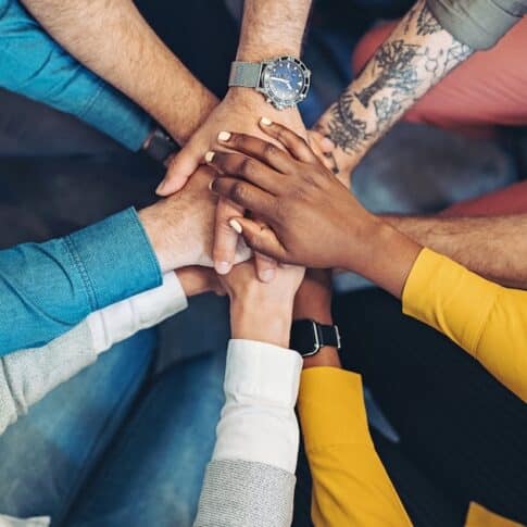 Group of business persons standing in a circle and stacking hands
