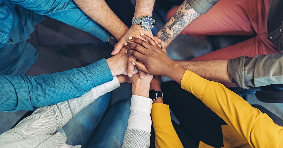 Group of business persons standing in a circle and stacking hands
