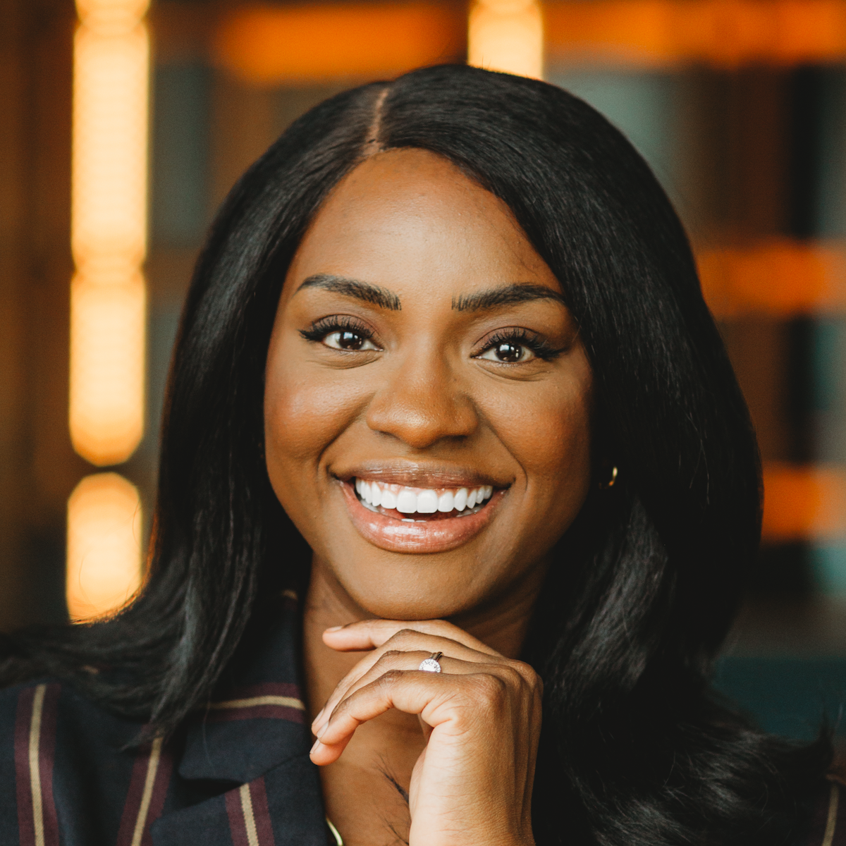 Smiling woman with hand under chin indoors.